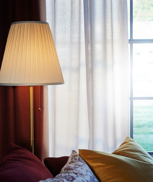Лампа пред прозорец със завеси.